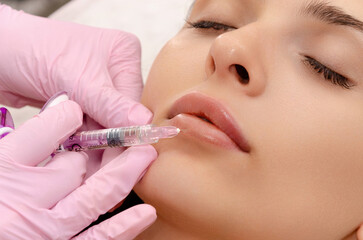 young woman gets filler injection in her lips at a beauty salon. lip augmentation procedure.