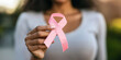 © Gabriela - Woman holding a pink ribbon to prevent breast cancer