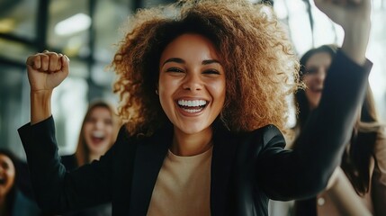 Poster - Exuberant Celebration: A young woman, dressed in a sleek black blazer, radiates joy and excitement, with her arms raised in victory, surrounded by a group of smiling colleagues.