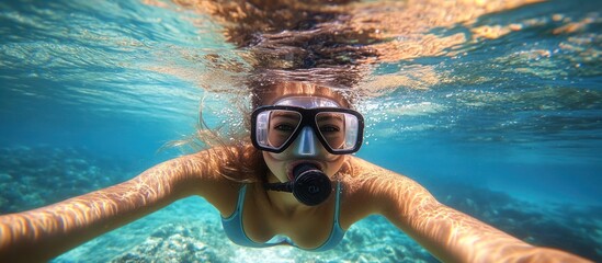 A woman wearing a snorkel and mask swims underwater.