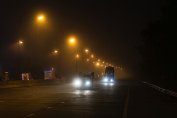 Cars on the road in the fog and drive car carefully.The car is driving along the dangerous foggy road.Traffic danger from fog on highway in the morning time.