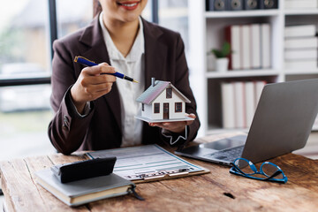 Guarantee, Mortgage, agreement, contract, Signing,asian woman work at desk reading agreement document to sign land loan with real estate agent or bank officer, insurance concepts.
