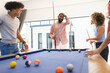 © Wavebreak Media - Playing pool, diverse friends enjoying fun hangout together, smiling and laughing, at home