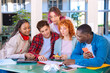 © alfons - Multiracial group of five happy teenage students talking with university notes. and smartphones