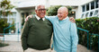 © KayExam/peopleimages.com - Outdoor, hug and old men with smile, funny and support with retirement, nature and joyful. Nursing home, best friends and senior people with embrace, garden and laughing with happiness and reunion