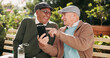 © KayExam/peopleimages.com - Outdoor, funny and senior men with cellphone, typing and retirement with humor, texting and message. Pensioner, friends and old people on bench, smartphone and mobile user in park, network and joke