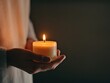 © Mnt - A serene moment captured as a person holds a glowing candle, creating a peaceful ambience in a dimly lit environment.