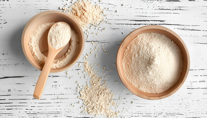 Bowl and spoon with active dry yeast on white wooden table