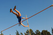 © Michalis Palis - Female pole vaulter clearing the bar under blue sky