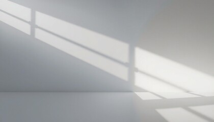 Sunlight casts a shadow of a window on a white wall and floor.