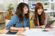 © wirojsid - Asian female designers collaborating with tablet and color swatches for creative project