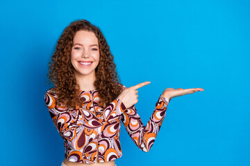 Wall Mural - Photo portrait of lovely young lady point hold empty space dressed stylish colorful garment isolated on blue color background