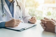 © Martí Rosselló - Doctor Taking Notes During Medical Consultation with Patient Close-up of a doctor writing notes on a clipboard while consulting with a patient, symbolizing healthcare and medical care.