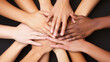 © Tossakan Photos - An image of multiple hands placed together in a show of unity and teamwork.