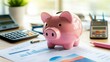 © sarun - A well-worn pink piggy bank sitting on a desk, surrounded by financial documents and a calculator, symbolizing personal savings goals.