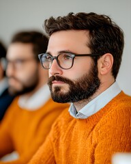 Focused man in orange sweater during a meeting