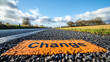 © Ruslan - The sign 'Change' on the asphalt of a highway between fields on a sunny day