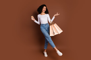 Poster - Full body portrait of nice young woman hold bags coffee wear pullover isolated on brown color background