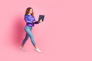 Wall Mural - Full size photo of pretty young woman jump run empty space laptop wear pullover isolated on pink color background