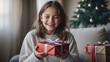 © NewFresh  - Portrait of smiling girl holding gift box while sitting on sofa at home