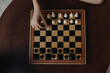 © SHOTPRIME STUDIO - Person engaging in an intense game of strategy on a wooden table with a classic black and white chess board