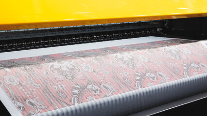 Leinwandbilder - A machine is printing a pattern on a piece of fabric. The pattern is floral and pink. The machine is yellow and black