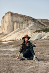 Wall Mural - Woman in hat enjoying nature's beauty with mountain backdrop and rock formation