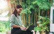© Have a nice day  - Asian business woman working outside typing on computer laptop device wireless remote communication technology, connectivity digital online freelance worker casual outdoor in nature at cafe sunlight.