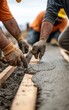 © Mind - Close-up of workers pouring concrete, showcasing hands at work with tools, focusing on craftsmanship and construction site activity.