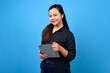 © Andri - confidence young asian business woman, female entrepreneur, holding tablet and smiling to camera isolated on blue background