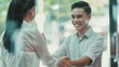 © VK Studio - Two professionals shake hands with genuine smiles in a brightly lit office lobby, symbolizing agreement, trust, and successful collaboration.