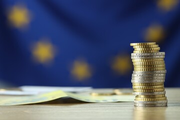 Stack of euro coins on wooden table, closeup