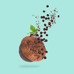 Wall Mural - Yummy muffin and chocolate chips in air on turquoise background