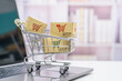 © William W. Potter - Online shopping, ecommerce and delivery service concept : Paper cartons with a shopping cart or trolley logo on a laptop, depicting customers order gadgets from online retailer store via the internet.