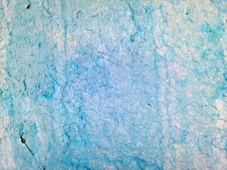 A blue and teal surface features a cracked and weathered appearance suggesting it may be old and exposed to the elements 