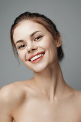 Wall Mural - Happy young woman with a beautiful smile showing white teeth on a grey background