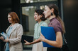 © qunica.com - Three professional women walking together outdoors, holding documents and discussing a successful business meeting. They appear confident and engaged, highlighting teamwork and collaboration.