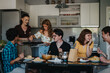 © qunica.com - A cheerful group of friends share a meal in a modern kitchen setting. The warm atmosphere captures friendship, community, and the joy of dining together.