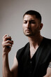 © Elina Leonova - The handsome man uses perfume. Bottle of perfume in a man`s hand. Fashion model