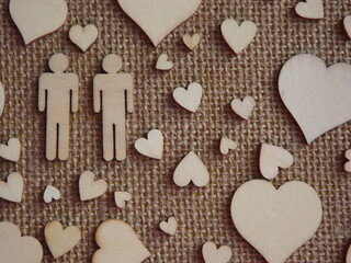 wooden hearts of different sizes and figurines of a man and a woman on jute fabric as a Valentine's day card. Declaration of love. High quality photo