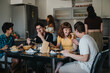 © qunica.com - A group of friends shares a laugh while having a casual meal in a modern kitchen setting. The atmosphere is warm and joyful, reflecting companionship and leisure.