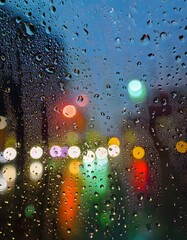 Wall Mural - Water drops on a glass with blurred city lights in the background
