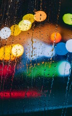 Wall Mural - Water drops on a glass with blurred city lights in the background