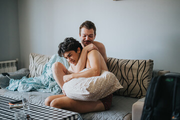 Wall Mural - Two male friends enjoy a playful wrestling match on the sofa, sharing laughter and camaraderie in a cozy home setting.