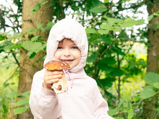 Wall Mural - girl in the forest shows edible red mushroom