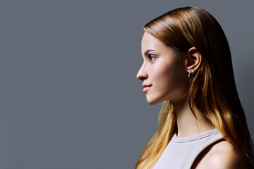 Headshot portrait in profile beautiful smiling young woman with red hair on gray background