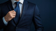 © Michael - Businessman fixing his tie knot in a suit and shirt against a navy blue backdrop