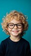 © NK - Smiling child boy with curly hair wearing glasses against blue background