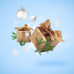 Poster - Gift boxes, Christmas balls, fir tree branches and decorative snowflakes in air on light blue background