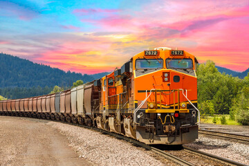 Wall Mural - freight train pulling cargo with a beautiful sunset in the background close to Whitefish, Montana